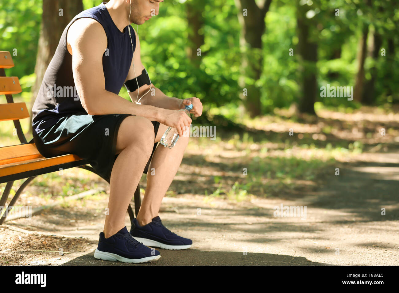 Sporty man with bottle of water resting after running in park Stock ...