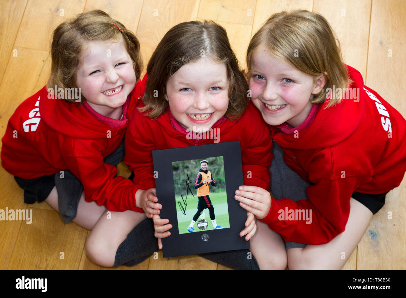 Three football fan / fans / primary school girls / children / kids with a signed autograph photograph of Manchester United & England soccer player Jesse Lingard. Stock Photo