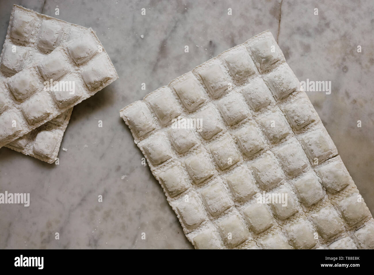Traditional raw ravioli, on the marble of the kitchen, ready to boil on ...