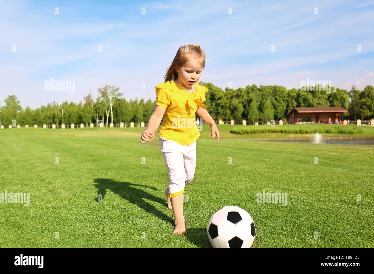 Cute little girl playing football in park on sunny day Stock Photo - Alamy