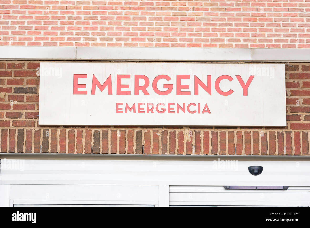 A red emergency directional sign and marker in English with Spanish