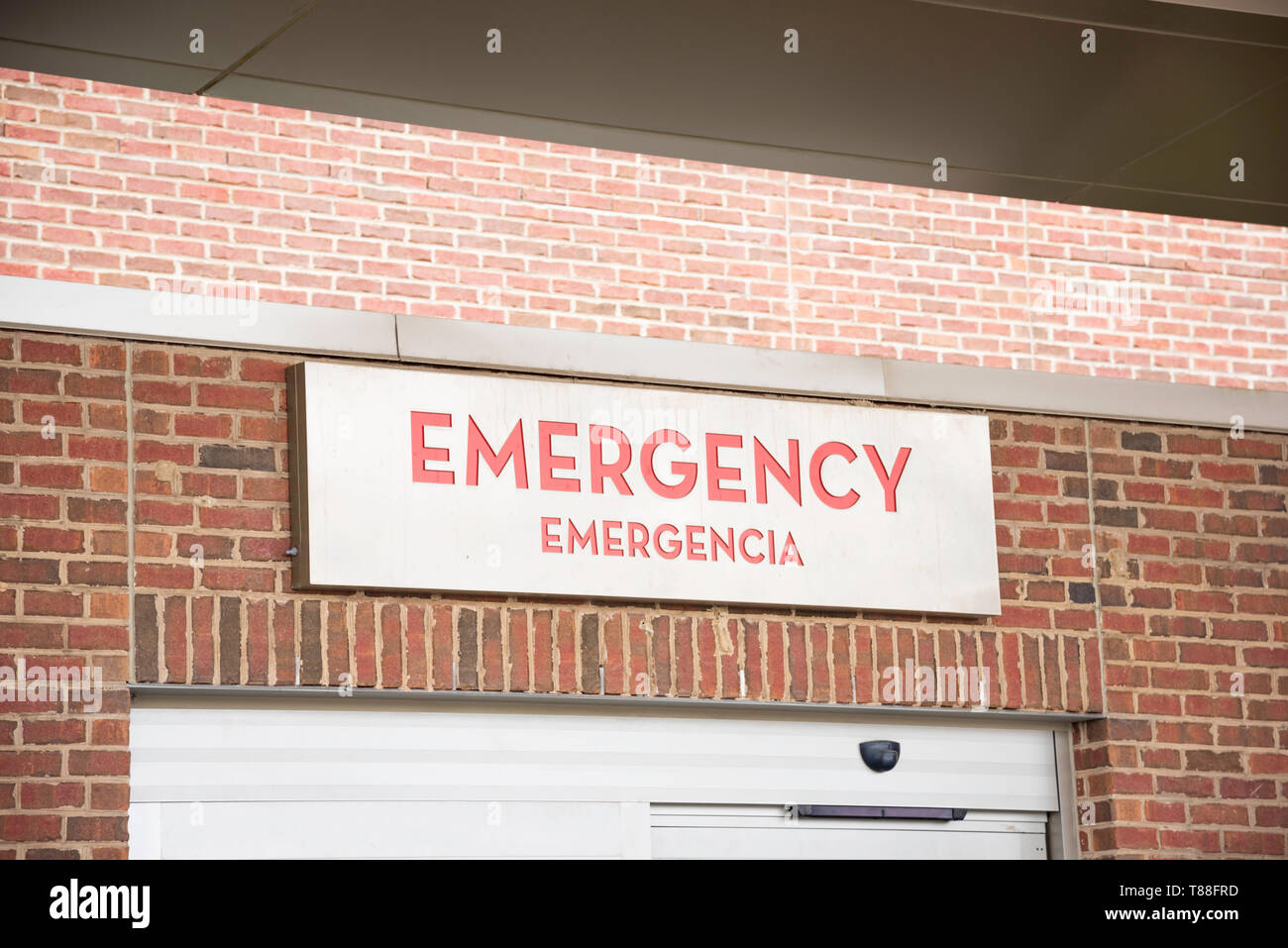 A red emergency directional sign and marker in English with Spanish