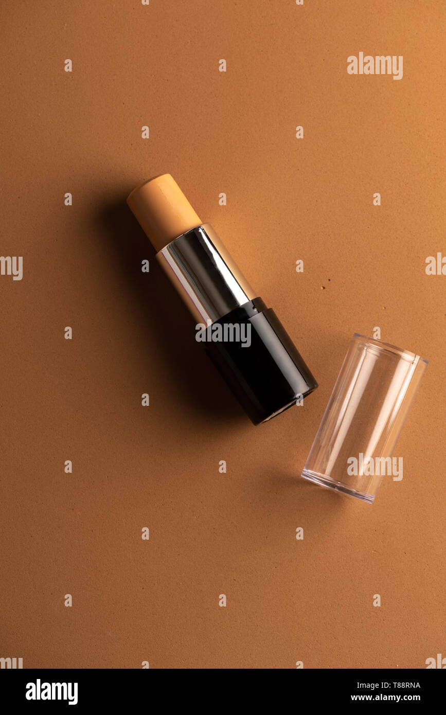 concealer stick, on geometric backgrounds, in shades of brown. Product and makeup concept from above Stock Photo