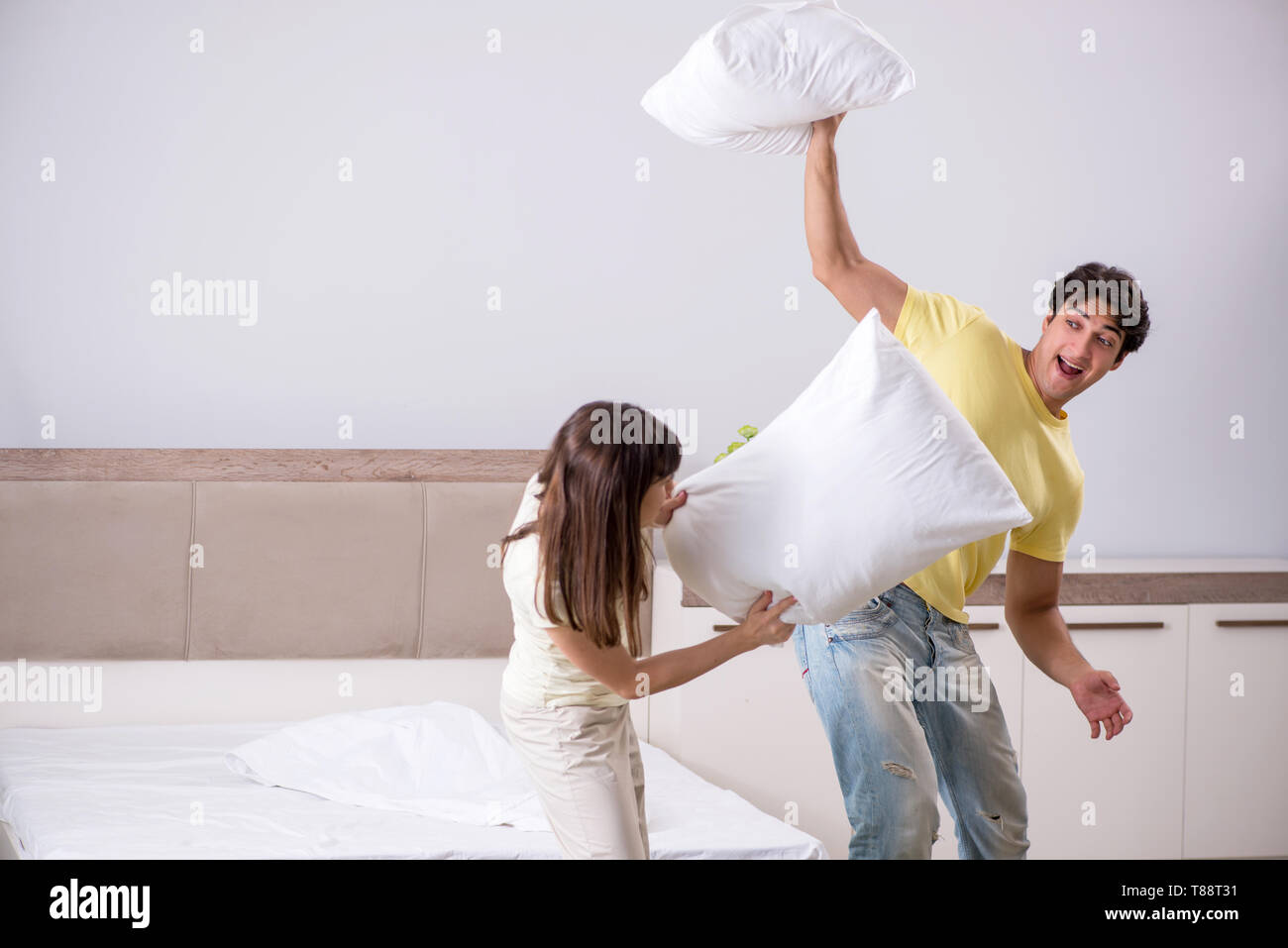 Wife and husband having pillow fight in bedroom Stock Photo - Alamy