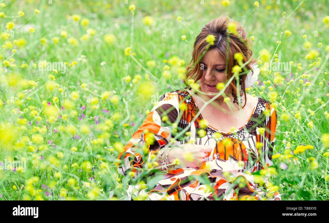 Attractive middle age woman sitting in daisies field positive emotions feeling life perception success, peace of mind concept. Space for text Stock Photo