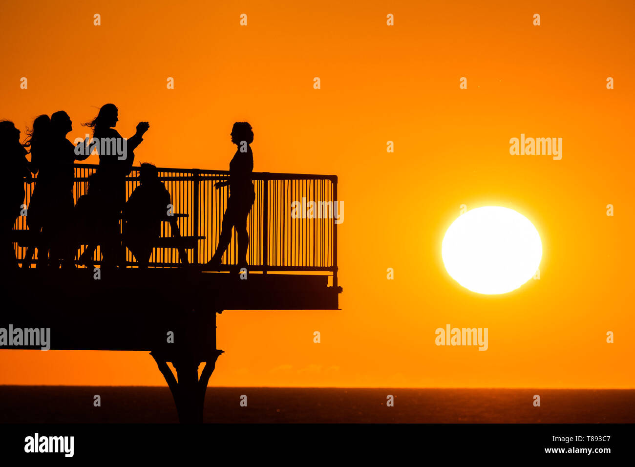 Aberystwyth Wales UK, Saturday 11 May 2019  UK Weather: People are silhouetted  against the glorious setting sun as they stand on the pier in Aberystwyth on the Cardigan Bay coast, West Wales. The weather is set to get warmer again in the coming week after as period of unsettled cold conditions.   photo credit Keith Morris / Alamy Live News Stock Photo