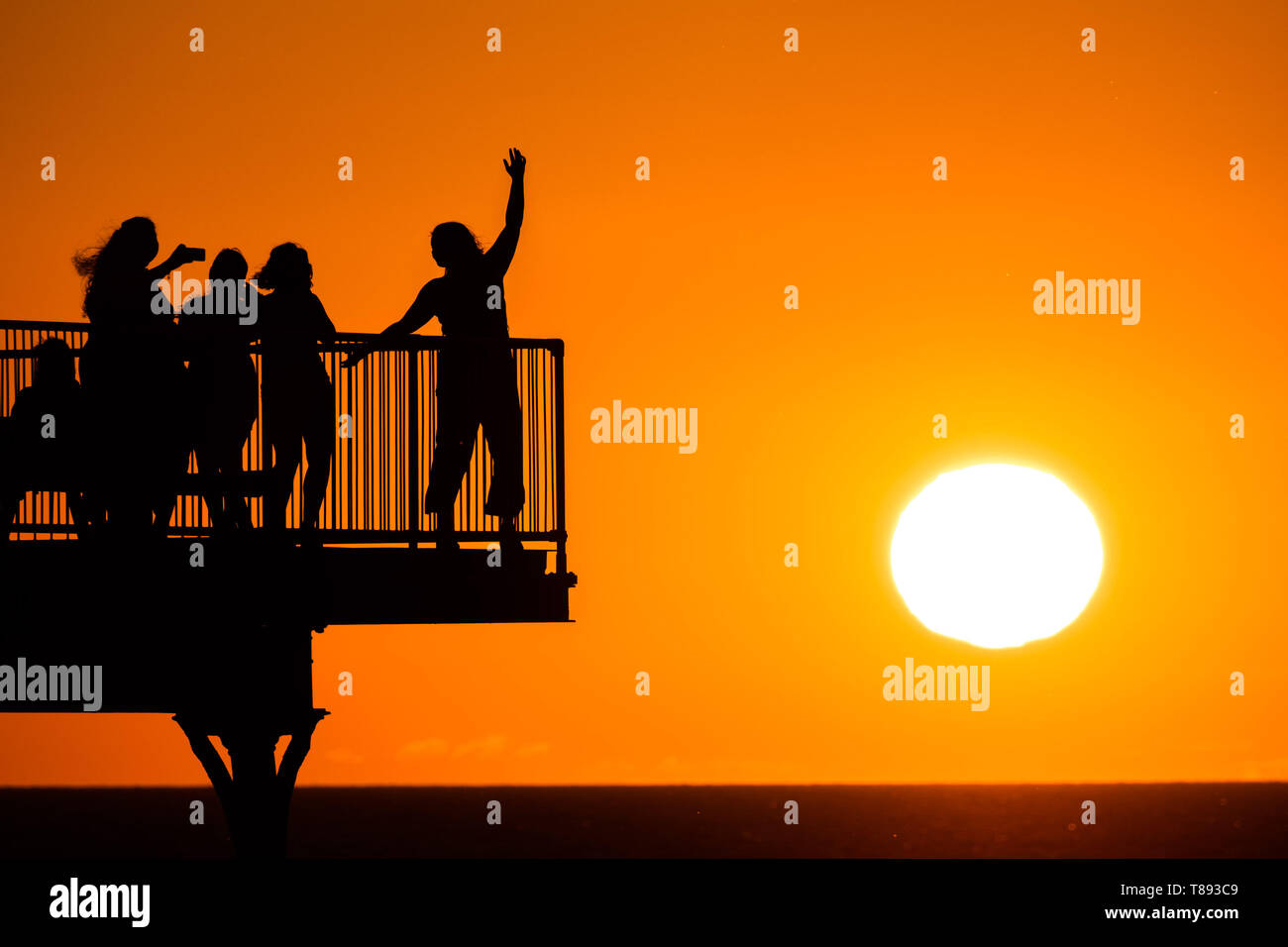 Aberystwyth Wales UK, Saturday 11 May 2019  UK Weather: People are silhouetted  against the glorious setting sun as they stand on the pier in Aberystwyth on the Cardigan Bay coast, West Wales. The weather is set to get warmer again in the coming week after as period of unsettled cold conditions.   photo credit Keith Morris / Alamy Live News Stock Photo