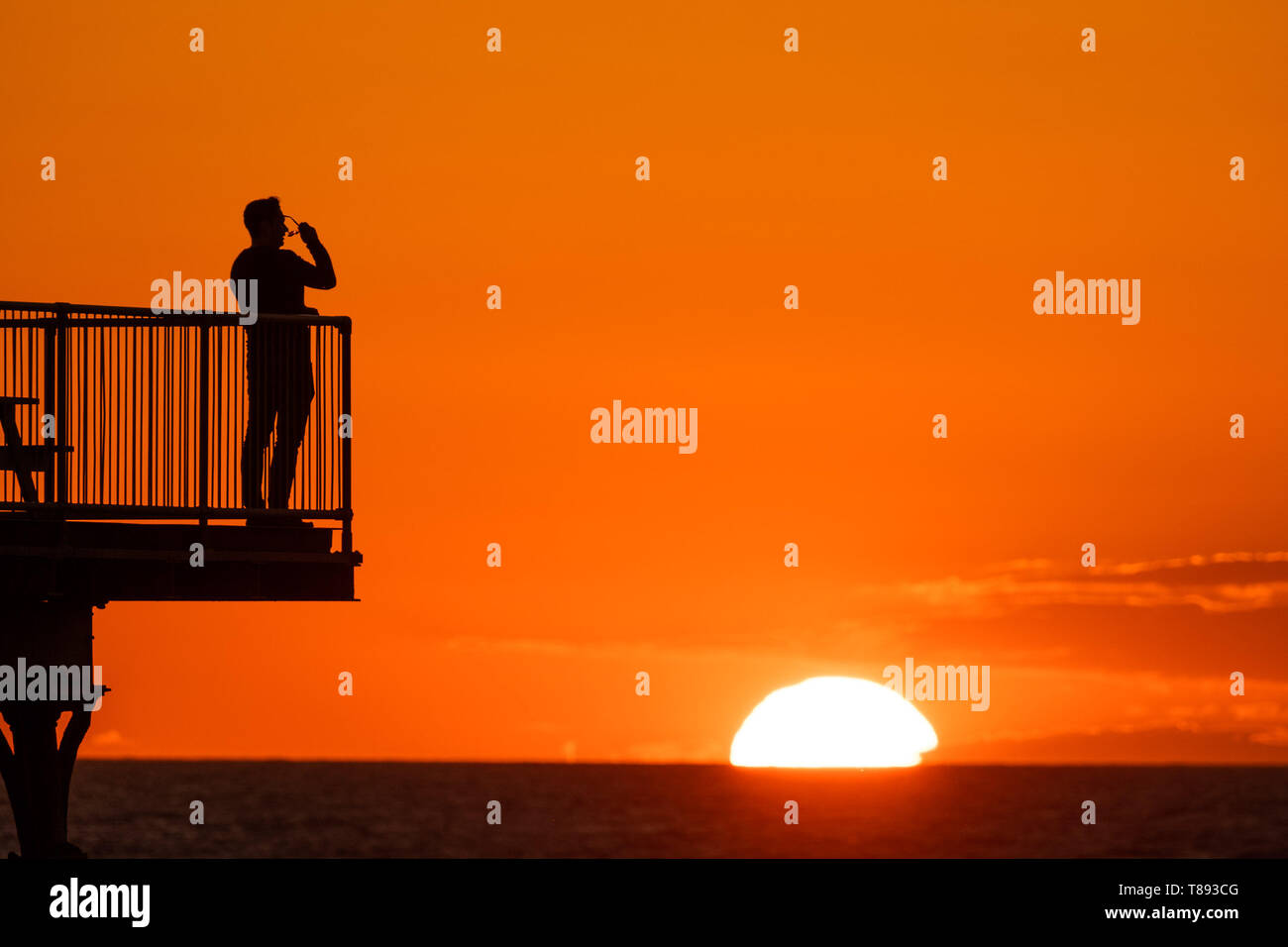 Aberystwyth Wales UK, Saturday 11 May 2019  UK Weather: People are silhouetted  against the glorious setting sun as they stand on the pier in Aberystwyth on the Cardigan Bay coast, West Wales. The weather is set to get warmer again in the coming week after as period of unsettled cold conditions.   photo credit Keith Morris / Alamy Live News Stock Photo