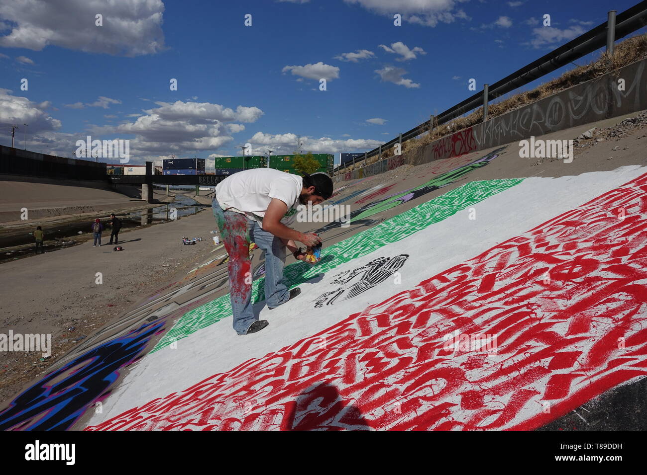 Ciudad Juarez, Mexico. 14th Jan, 2016. An artist from the USA is working in the canal of the Rio Bravo border river on a picture depicting the Mexican flag. A cross-border graffiti meeting with artists from both countries took place in the canal. Credit: David Peinado/dpa/Alamy Live News Stock Photo