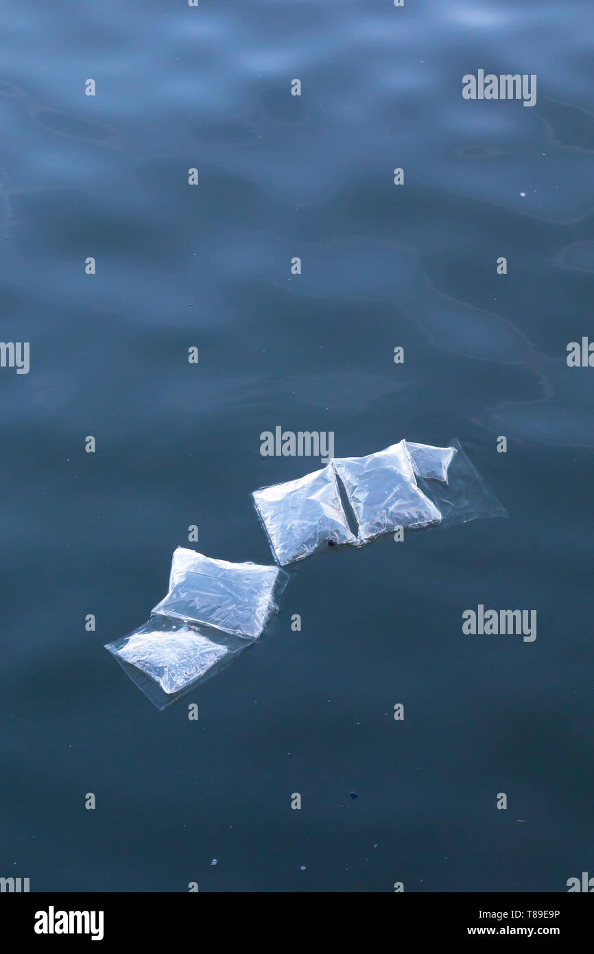 plastic marine pollution, underwater plastic bags and packaging floating semi submerged at