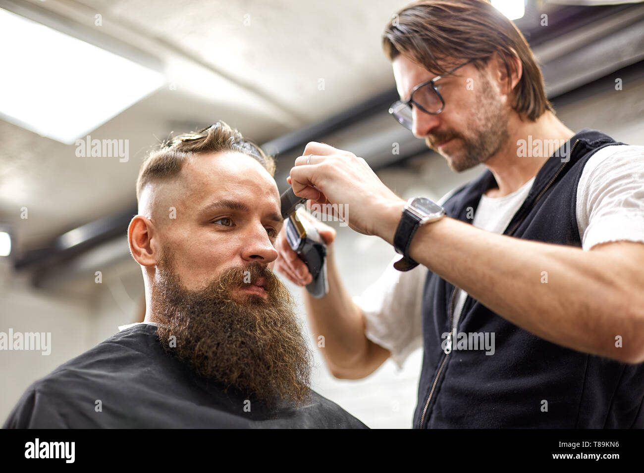 Master Cuts Hair And Beard Of Men In The Barbershop, Hairdresser Makes 