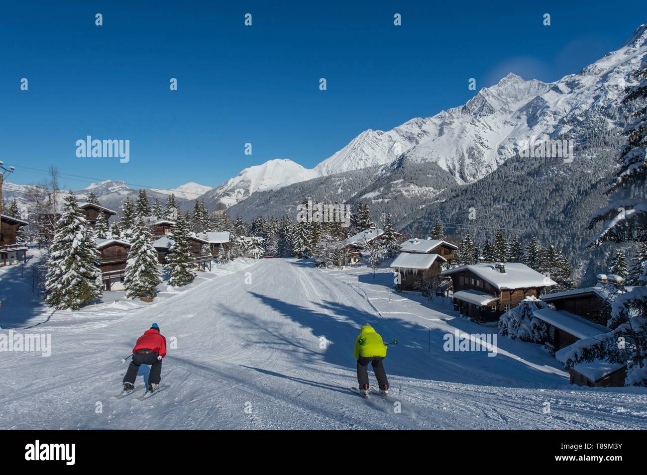 France, Haute Savoie, Massif of the Mont Blanc, the Contamines Montjoie, the short ski method on the ski slopes, 2 skiers in schuss position in the middle of chalets Stock Photo