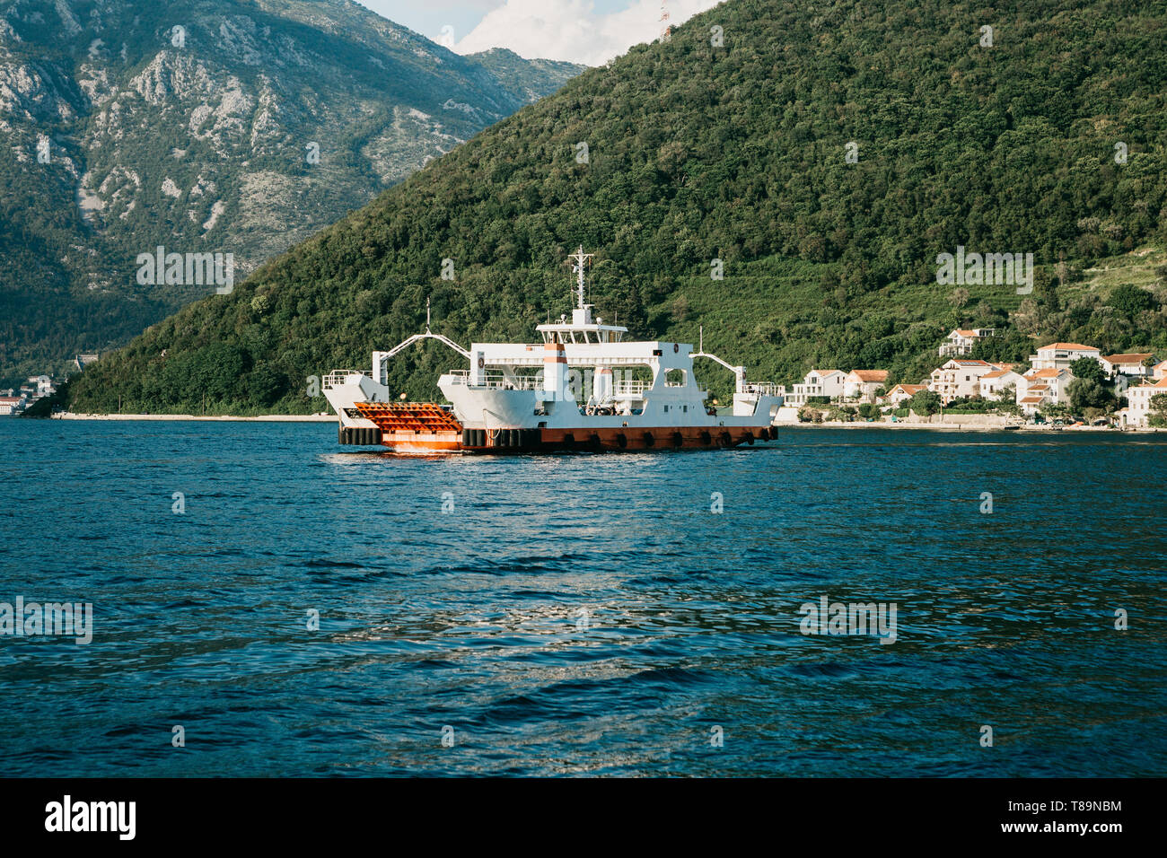 A ferry to transport vehicles and people crosses the bay in Montenegro and approaches the city. Stock Photo