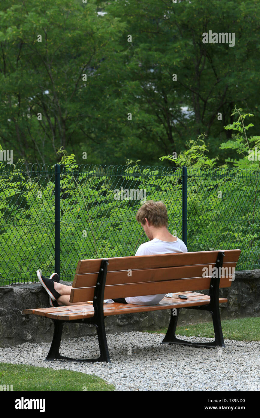 Jeune homme lisant sur un banc. Stock Photo