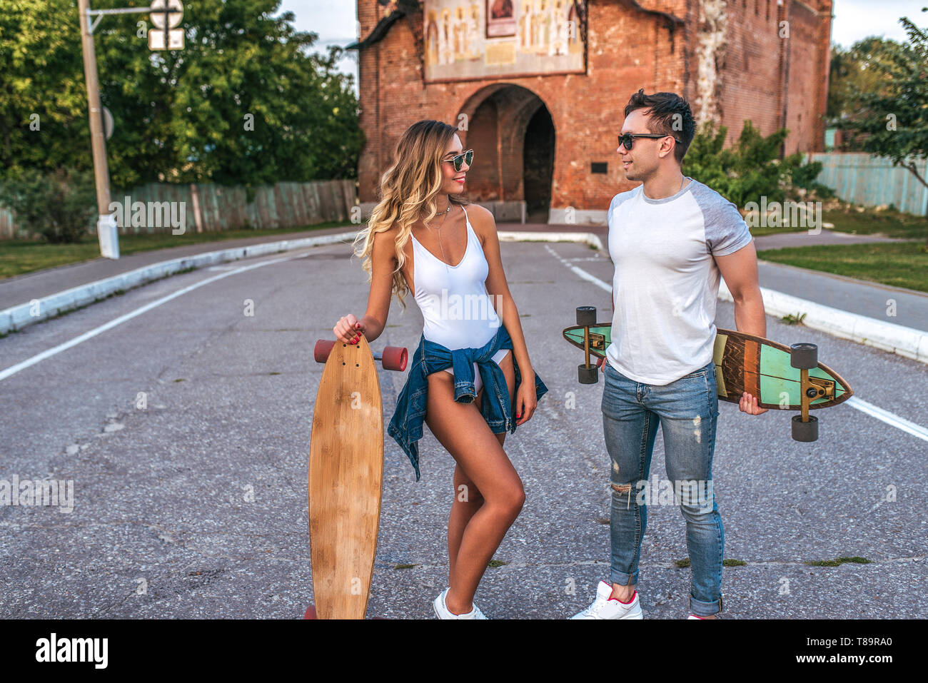 Young adult riding longboard on summer city street. Hipsters couple on  skateboards in urban area Stock Photo - Alamy
