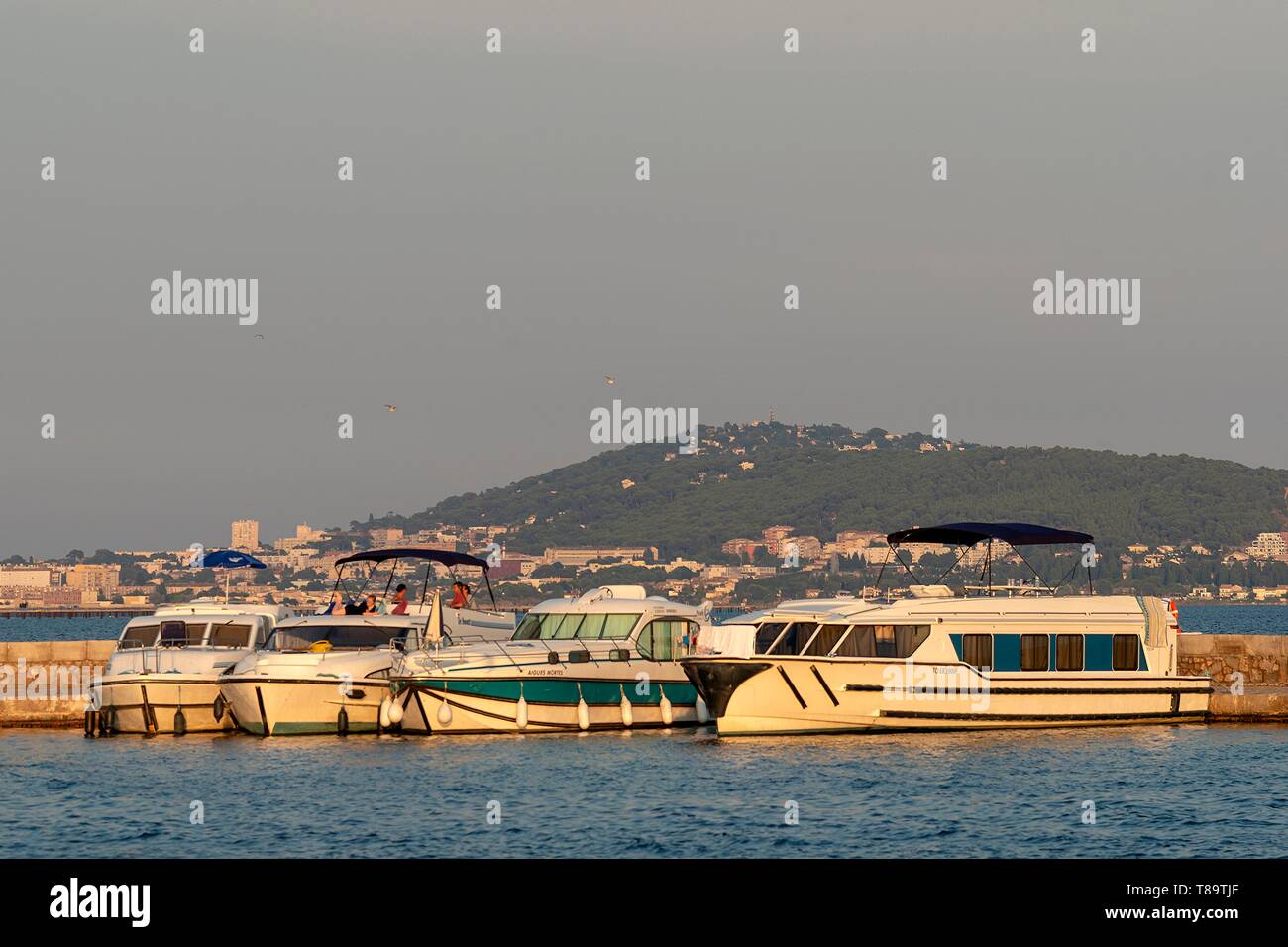 France, Herault, Meze, tourist boats alongside a quay with the Saint-Clair Mount in the background Stock Photo