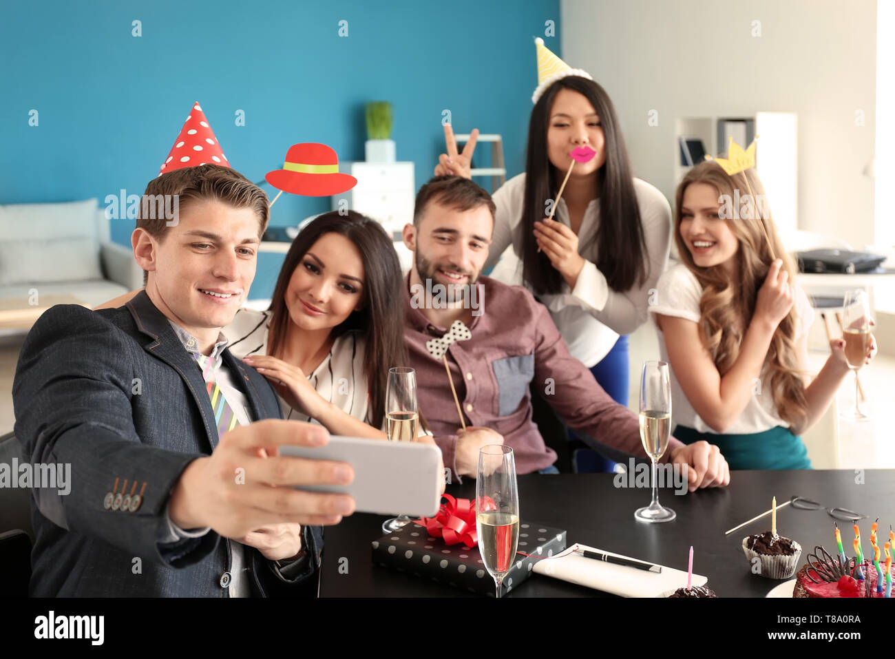 Young man taking selfie with his colleagues at birthday party in office Stock Photo