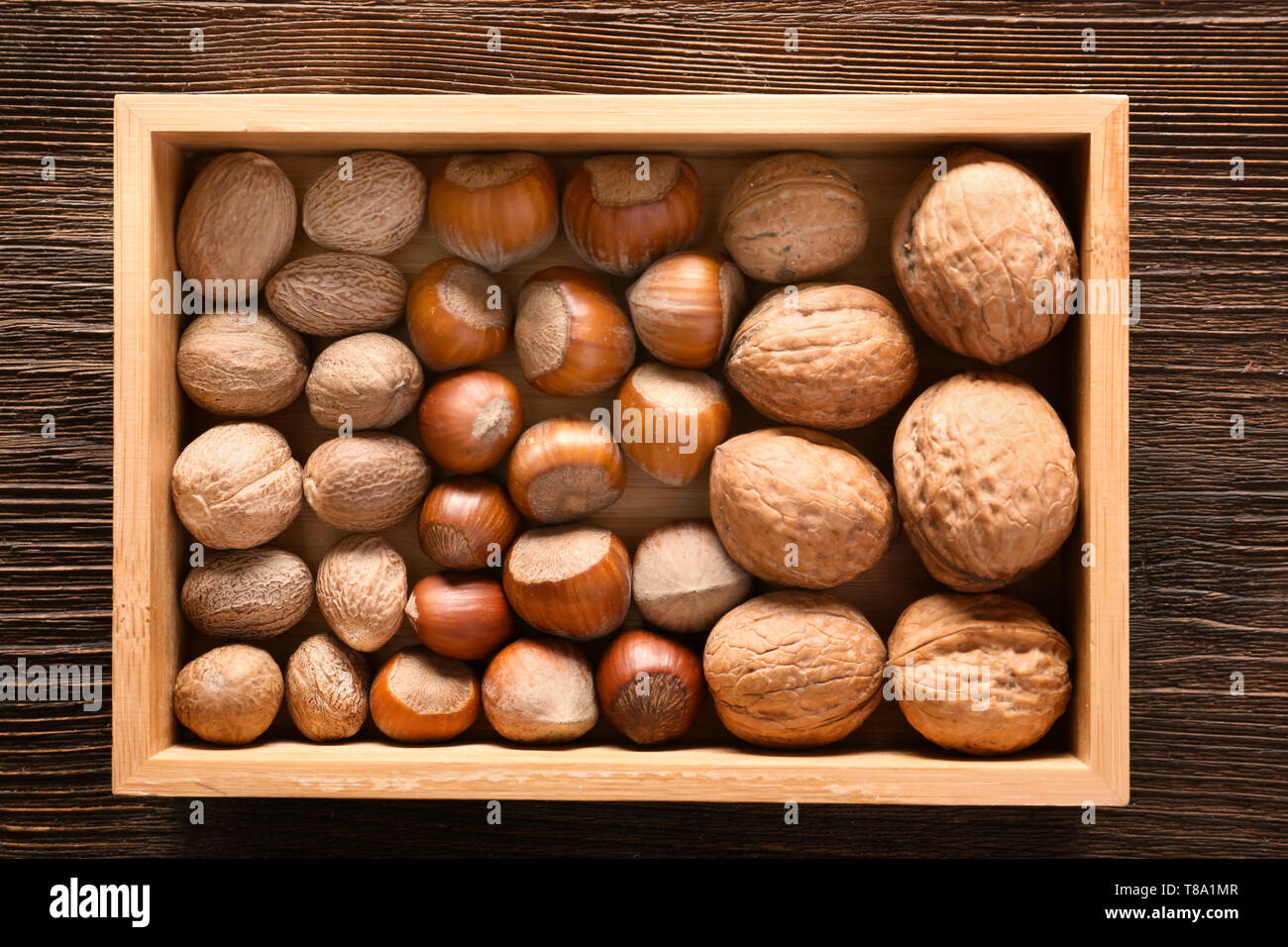 Wooden box with various nuts on table, top view Stock Photo