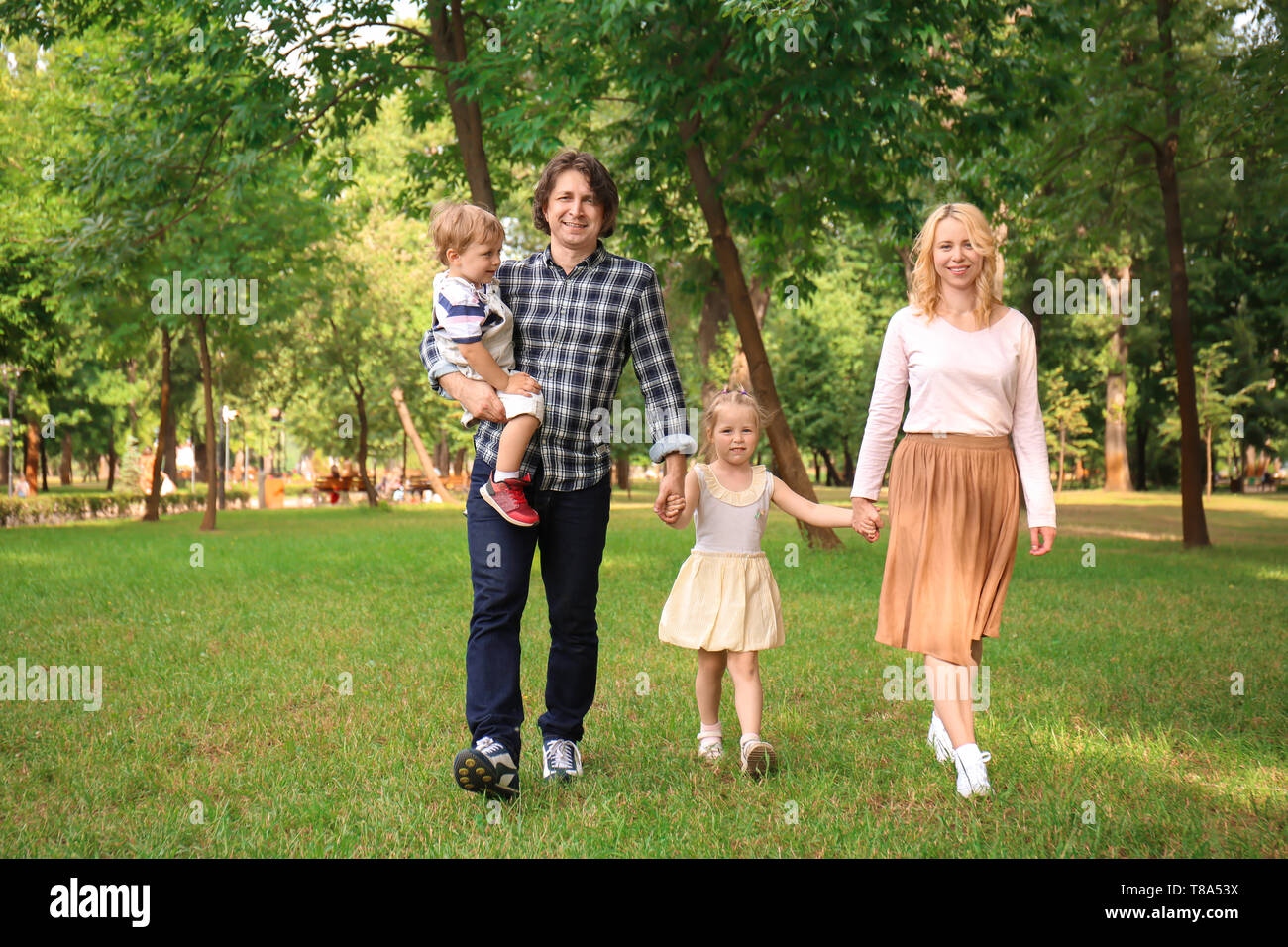 Happy family walking in green park Stock Photo - Alamy