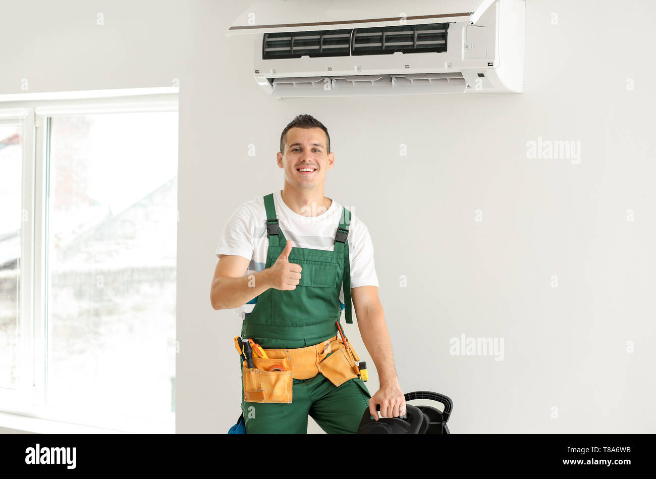 Electrician after successful repair of air conditioner indoors Stock Photo Alamy