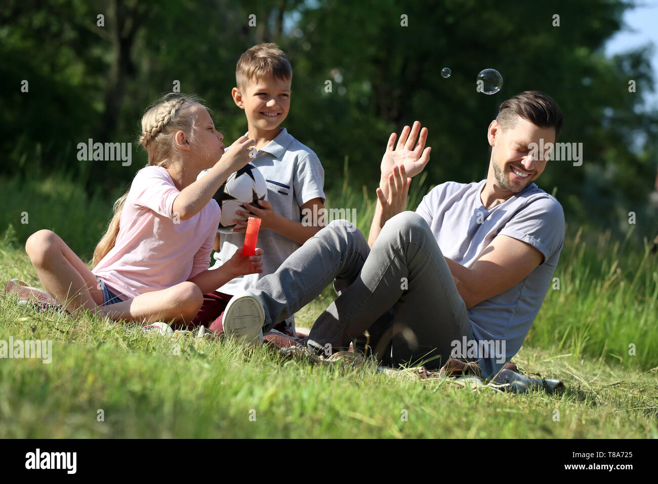 Man with his little children blowing soap bubbles in park Stock Photo ...