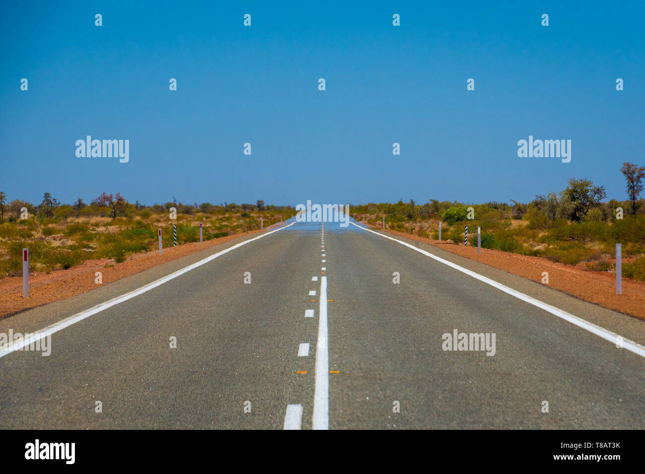 Mirage over straight endless road in Australia merging asphalt and sky Stock Photo