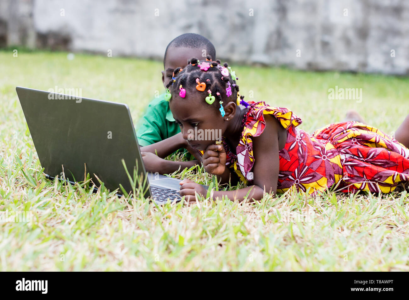 two children lying in the garden use a laptop Stock Photo - Alamy