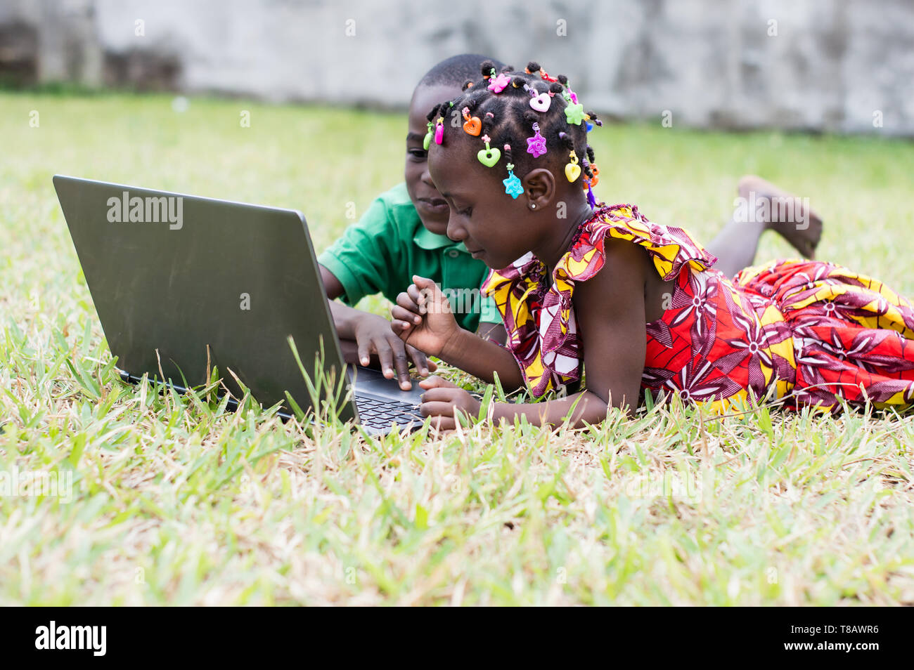Happy children using a laptop lying in the garden Stock Photo - Alamy