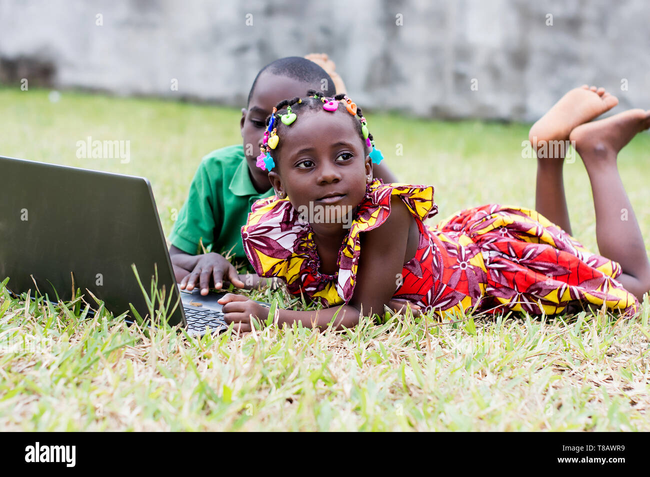 Happy children using a laptop lying in the garden Stock Photo - Alamy