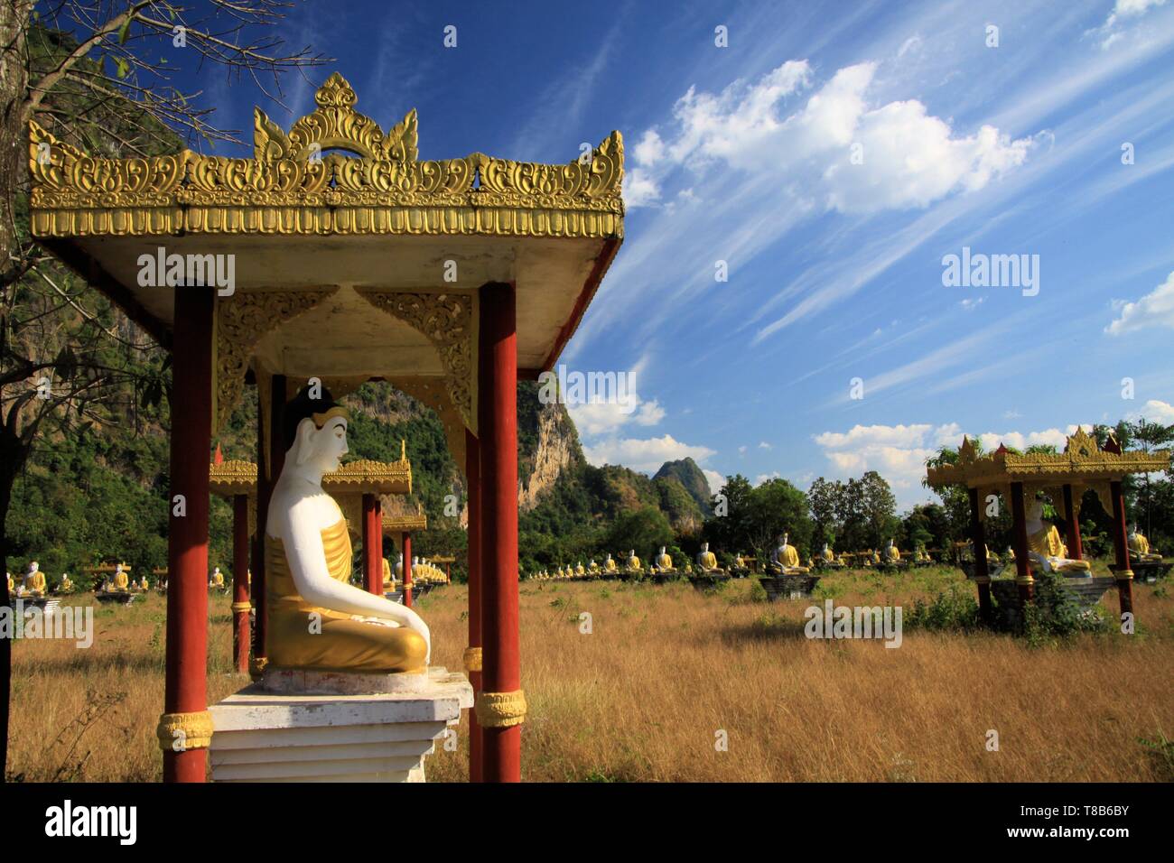 Lumbini Garden, Hpa An, Myanmar: View on secluded isolated valley with over 1000 sitting buddha statues in rows contrasting with blue sky and drifting Stock Photo