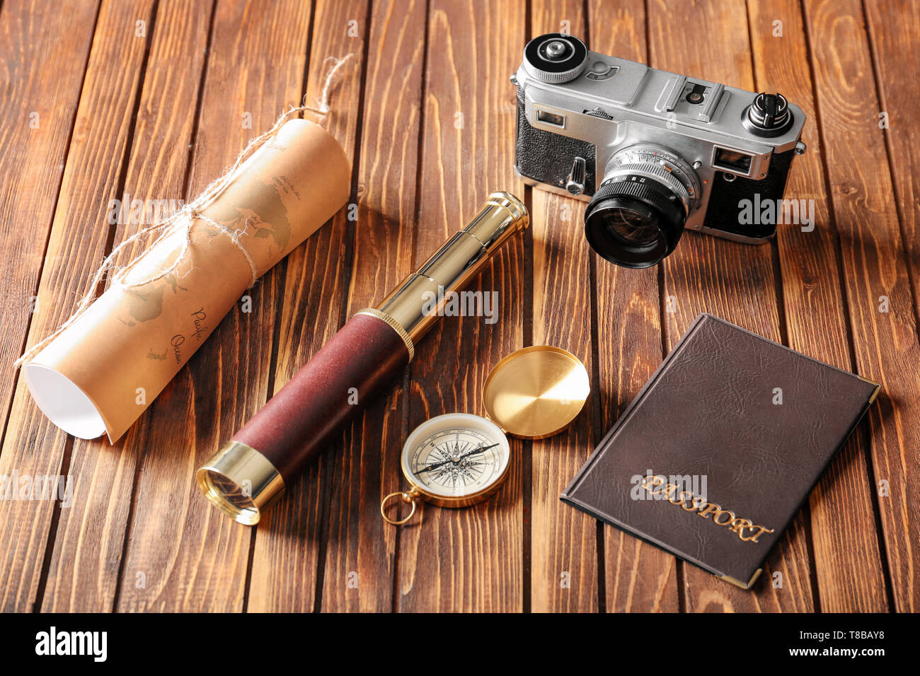 Vintage compass with spyglass, passport, map and photo camera on wooden table Stock Photo