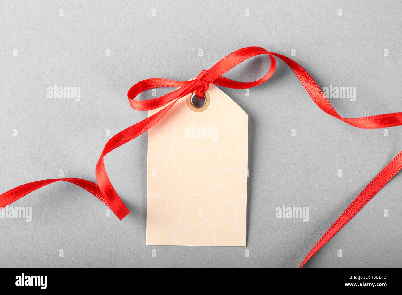 Blank gift tag with red ribbon on grey background Stock Photo - Alamy