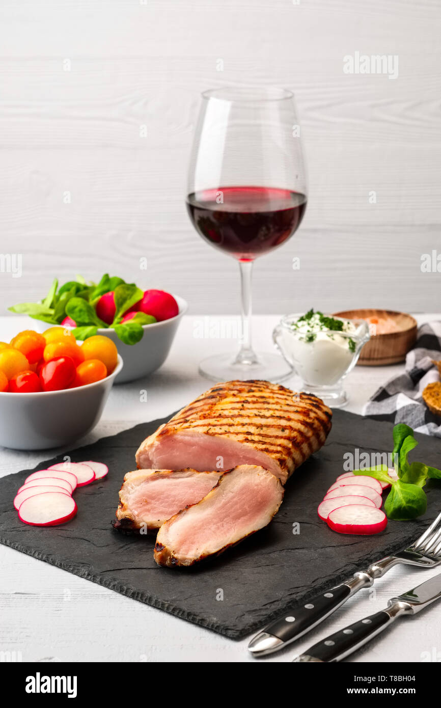 Grilled beef steak medium rare on stone board with fresh vegetables and glass of red wine Stock Photo
