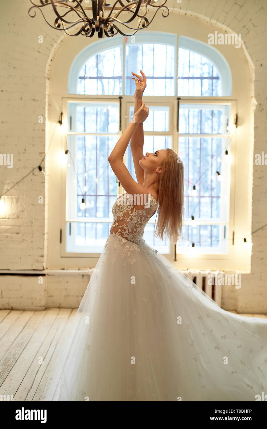 A graceful bride in a lace dress pulls 