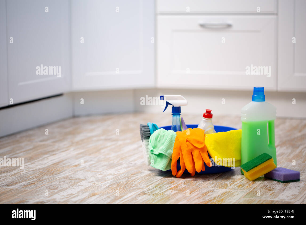 Set of cleaning supplies on floor in kitchen. Space for text. spring