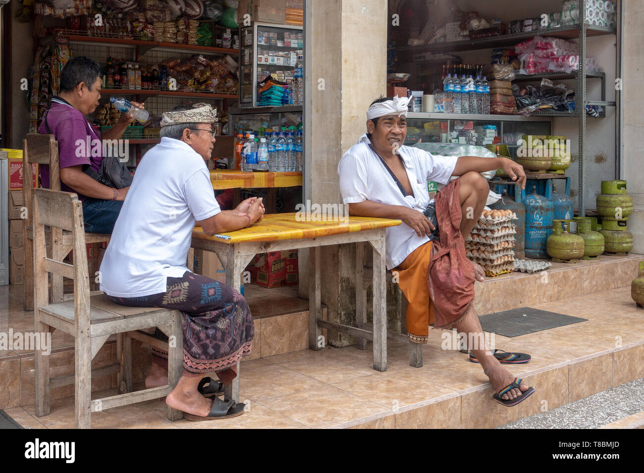 Balinese Men wearing Udeng headdress or a Balinees ikat kepala, relaxing in front of the shop Stock Photo