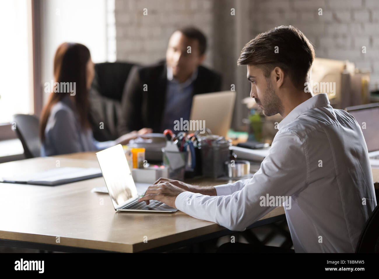 Office worker sitting at shared office working on notebook Stock Photo