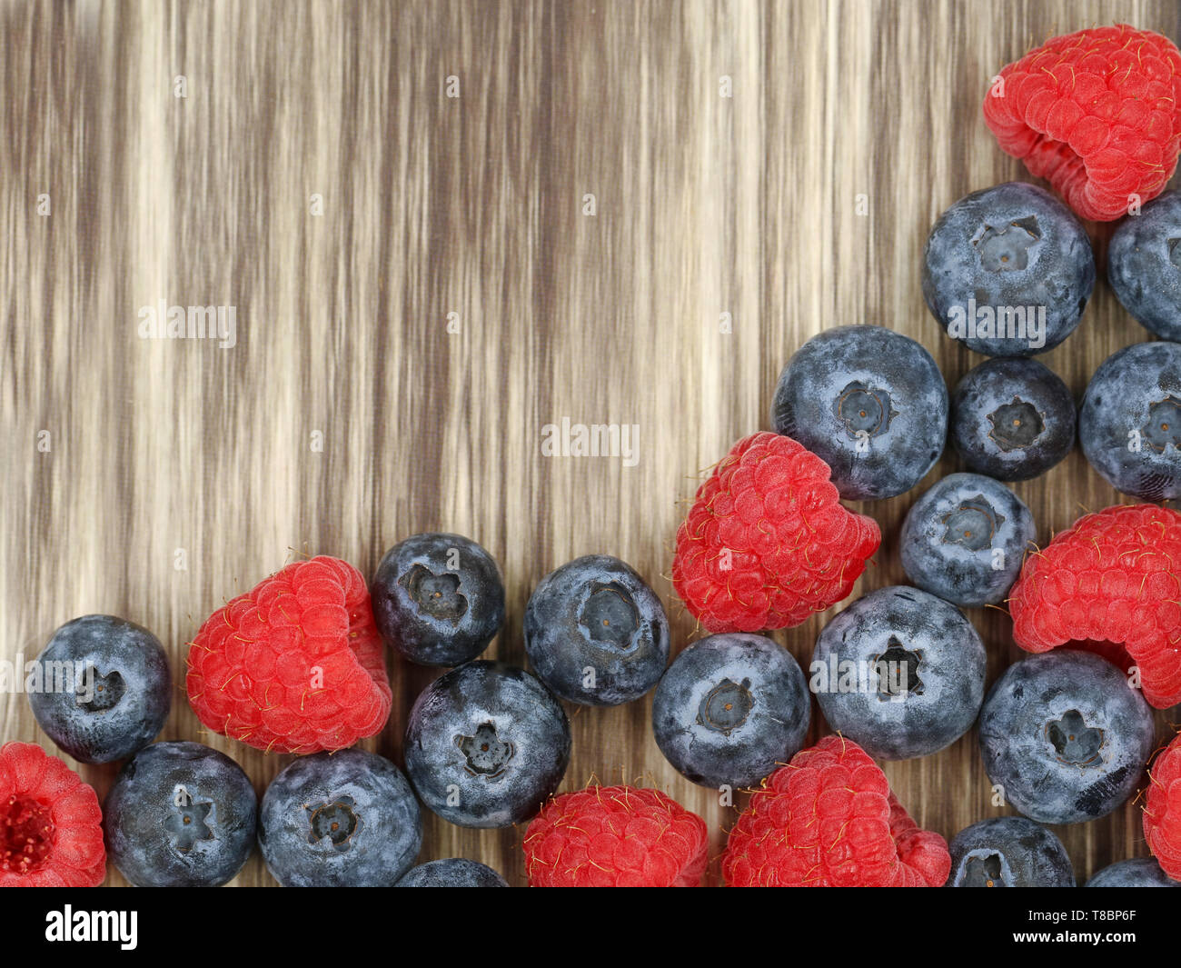 top view of raspberries and blueberries on wooden background with copy space, close-up Stock Photo