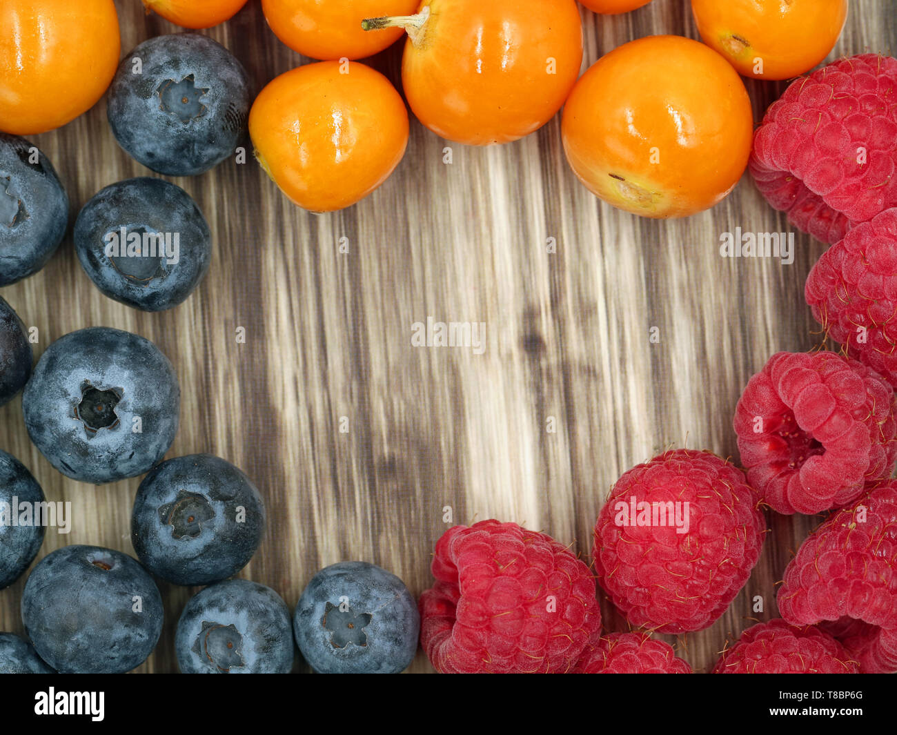 top view of raspberries, blueberries and berries of physalis on wooden background with copy space, close-up Stock Photo