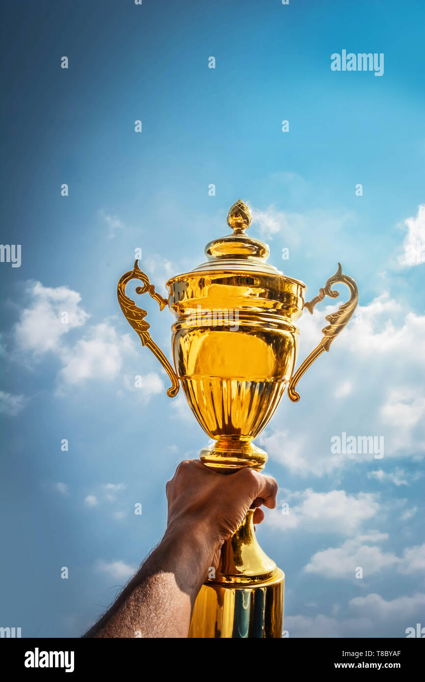 Holding up a gold trophy cup as a winner Stock Photo