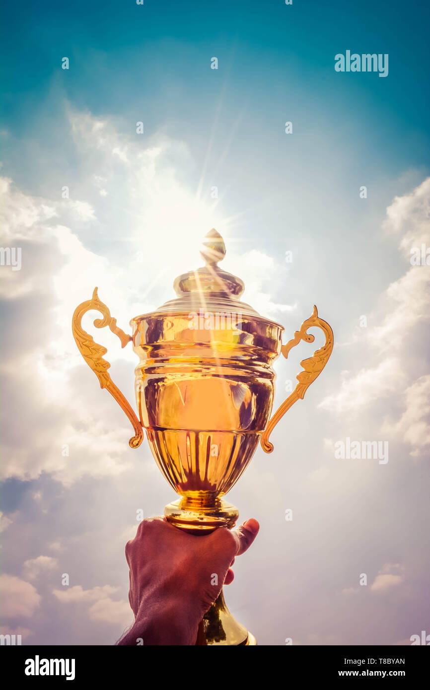 Holding up a gold trophy cup as a winner Stock Photo