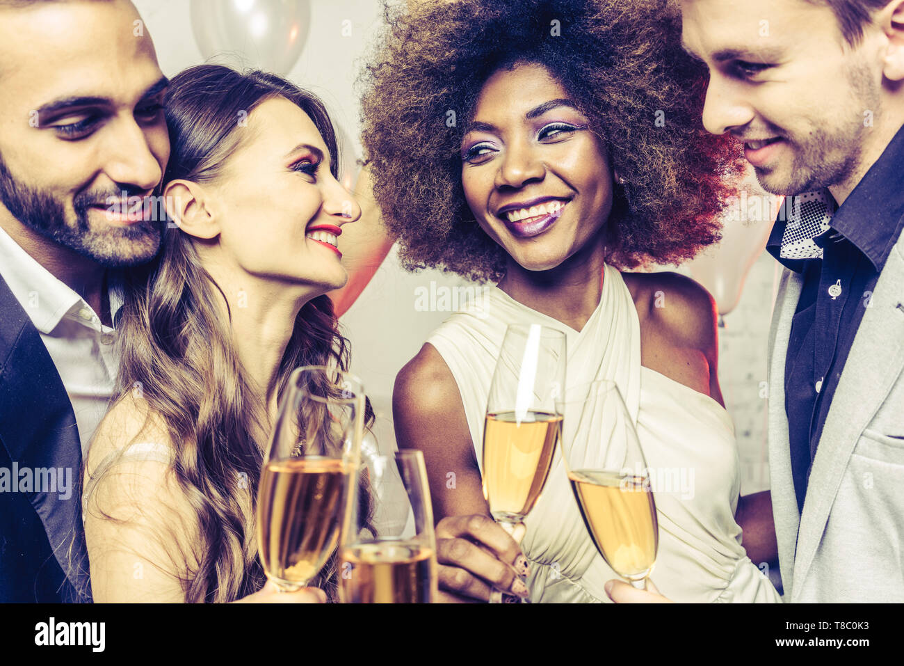 Men and women celebrating while clinking glasses with sparkling wine Stock Photo