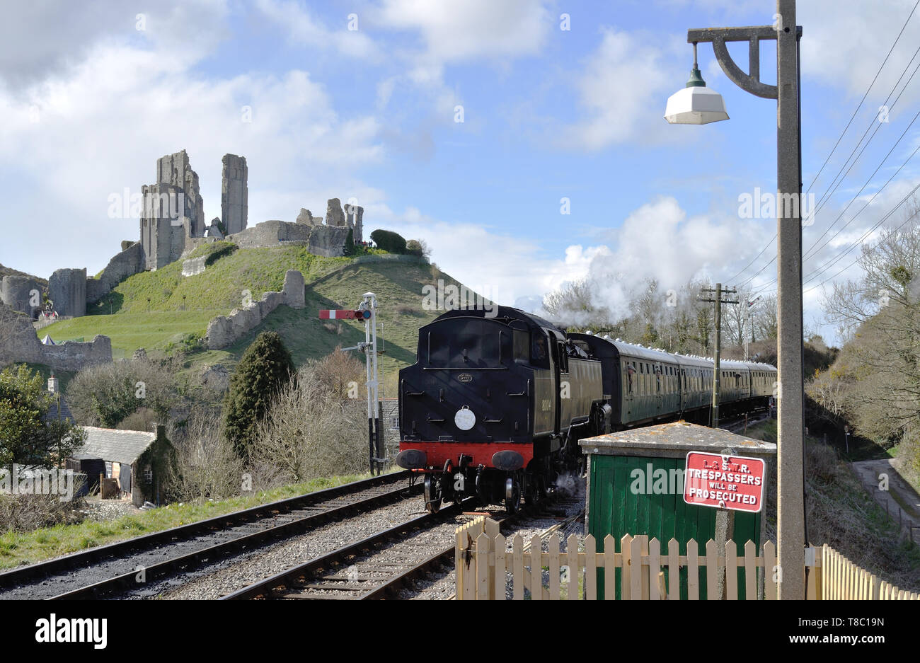 Preserved Standard Class 4MT 2-6-4T no. 80104 passes the castle ruins as it arrives at Corfe Castle station on the Swanage Railway in Dorset. Stock Photo