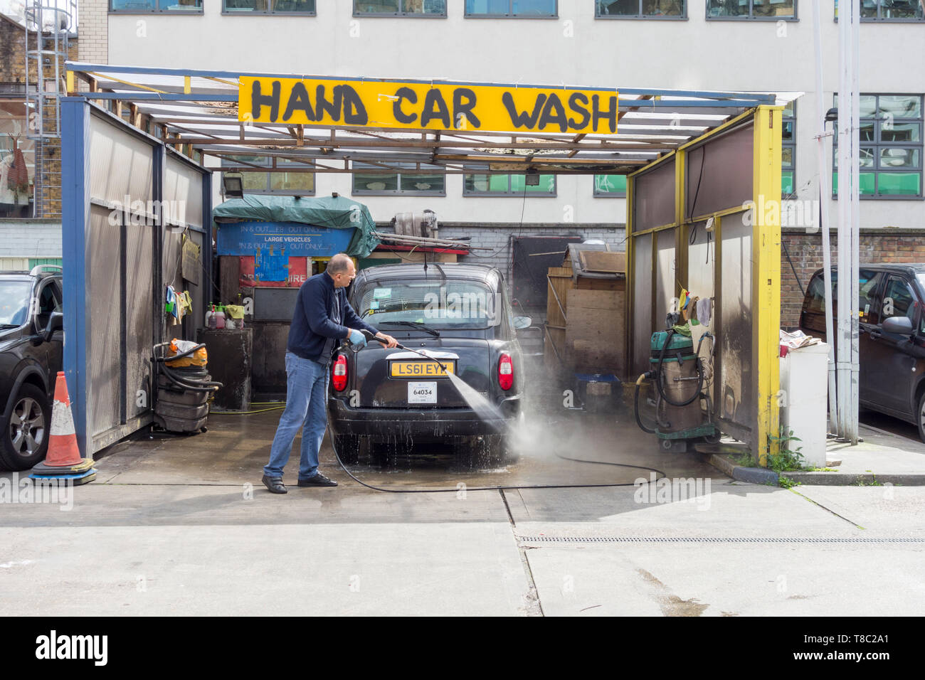A man washing a London black taxi cab in a