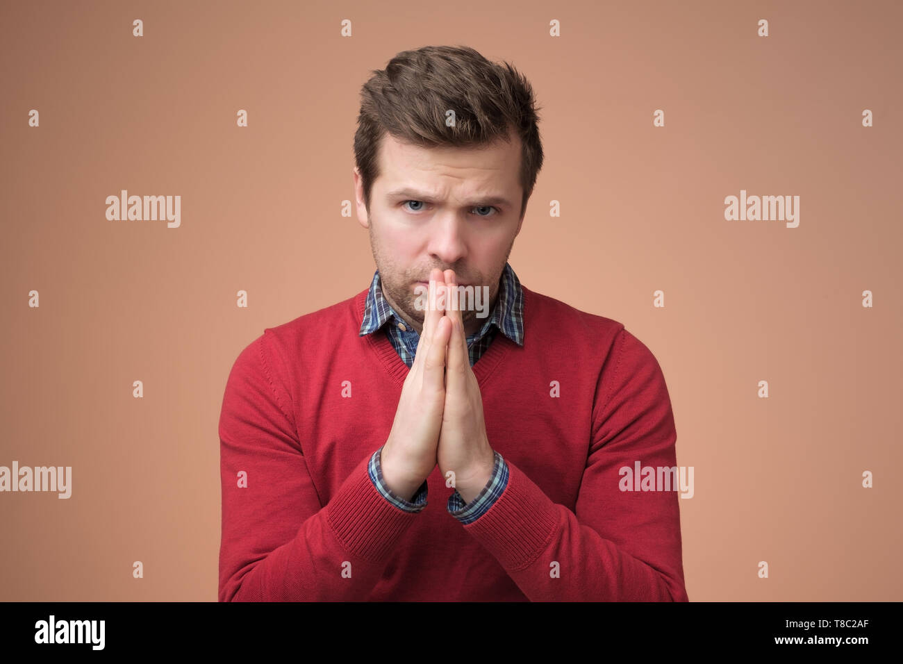 Desperate young man showing clasped hands, sorry for mistake Stock Photo