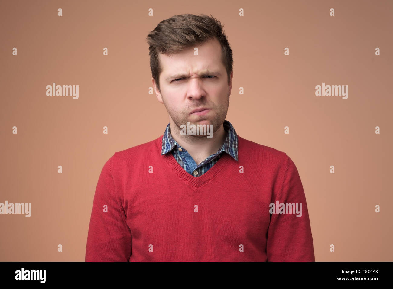 mature man in red sweater looking with disbelief expression Stock Photo