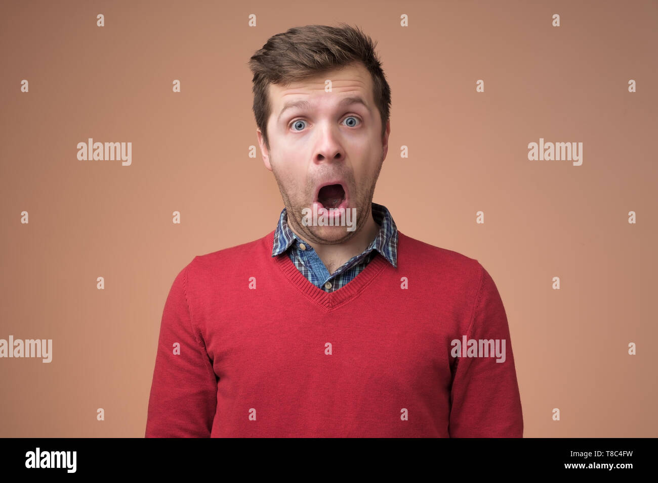 Shocked face of caucasian man in red sweater. Stock Photo