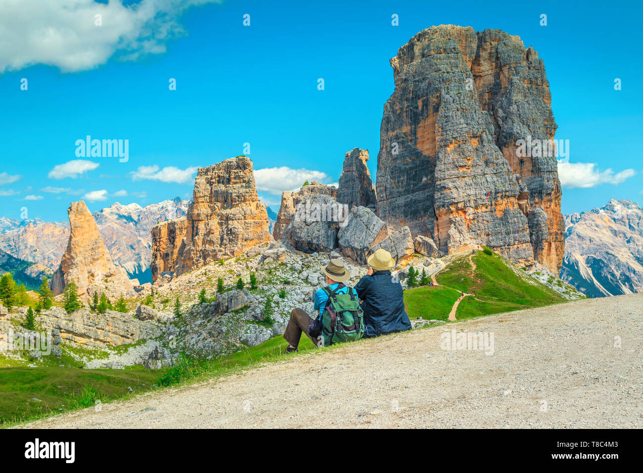 Happy elderly couple sitting in the mountains. Hiker senior couple with backpack relaxing near hiking trail and enjoying the beautiful view, Cinque To Stock Photo