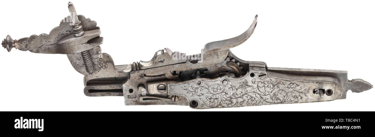 A German wheellock rifle with gear train, end of the 17th century Slightly swamped octagonal barrel with ten-groove rifled bore in 14 mm calibre, with dovetailed brass front sight and double folding rear sight with floral openwork. Extremely elaborately chiselled wheellock with captives between trophies, monsters, one Triton and lavish tendril decorations. Cover with floral engravings on the inside and gear train. Double set trigger. Carved stock made from grained thuja root wood with bone as well as tendril-shaped silver wire inlays between hors, Additional-Rights-Clearance-Info-Not-Available Stock Photo