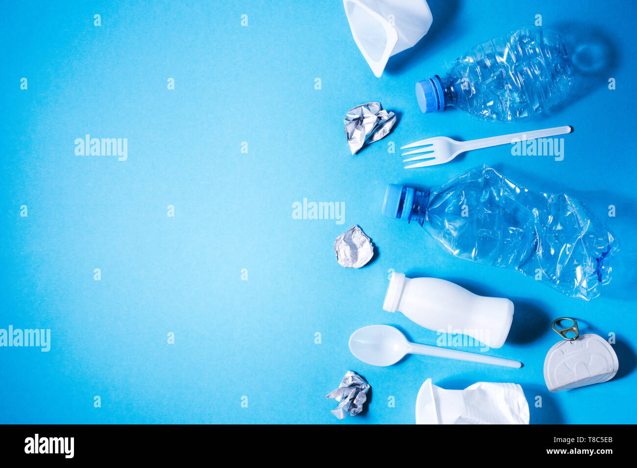 Plastic trash on blue background, eco concept image with copy space. Stock Photo